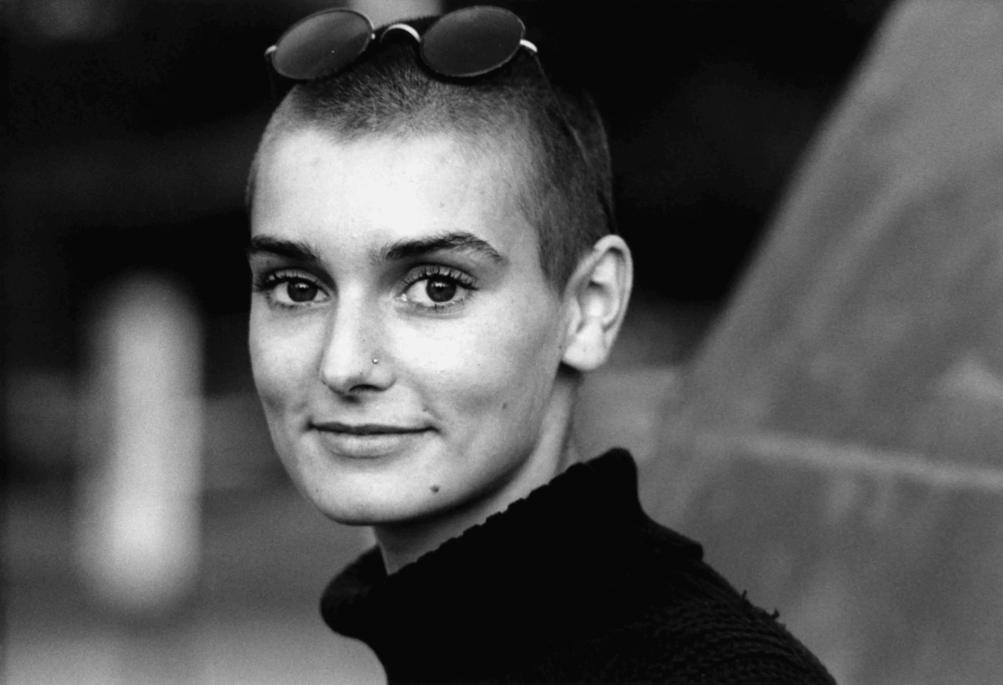 sinead O'Connor : This image is from Sinead O'Connor young days where she is seen wearing a goggles, with a neck high collar sweater.