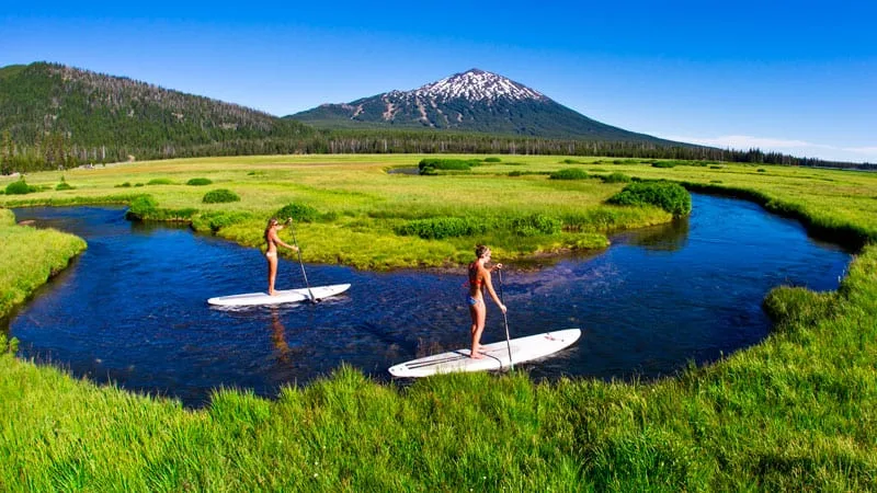 two girls paddle boarding the surfing board in a lake in Bend Oregon.