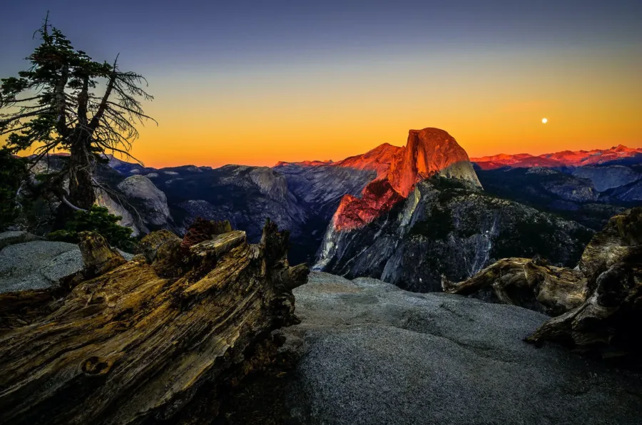 A beautiful evening scene from Yosemite Park rocky cliff. As sun is setting down, sky brightens up by birght orange, white and dark purple colours.